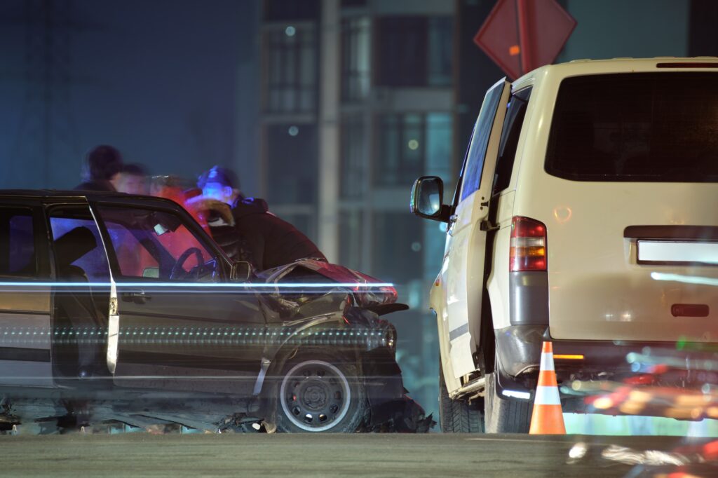 Damaged in heavy car accident vehicles after collision on city street crash site and silhouette of