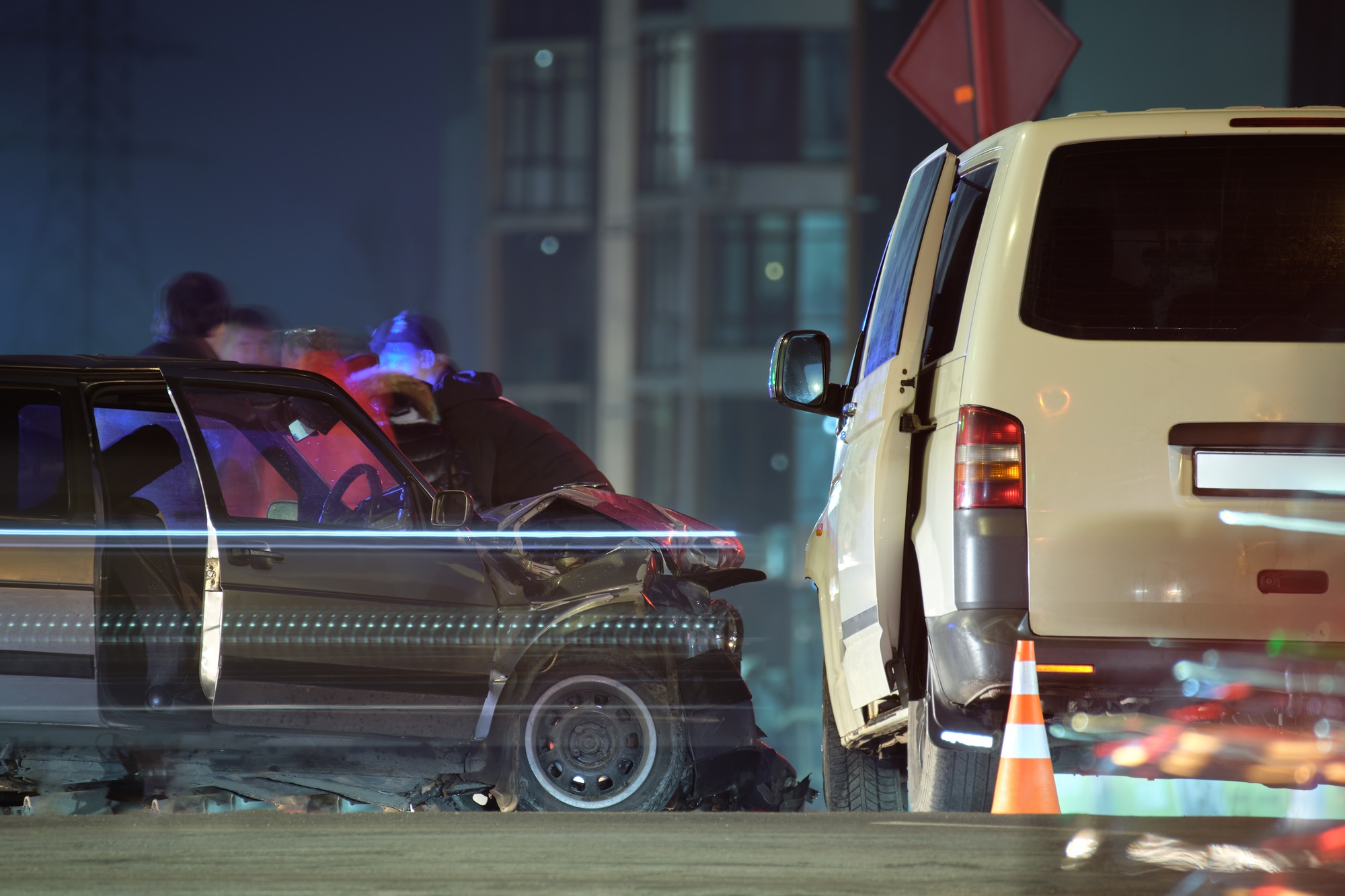 Damaged in heavy car accident vehicles after collision on city street crash site and silhouette of